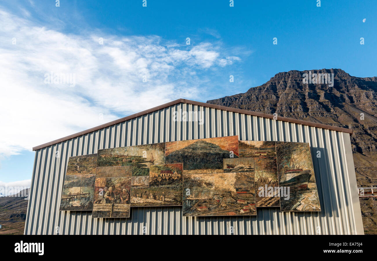 Murali dell'artista spagnolo Baltasar Samper, raffiguranti la storia dell'industria locale della pesca su edificio Eskifjordur in Islanda Foto Stock