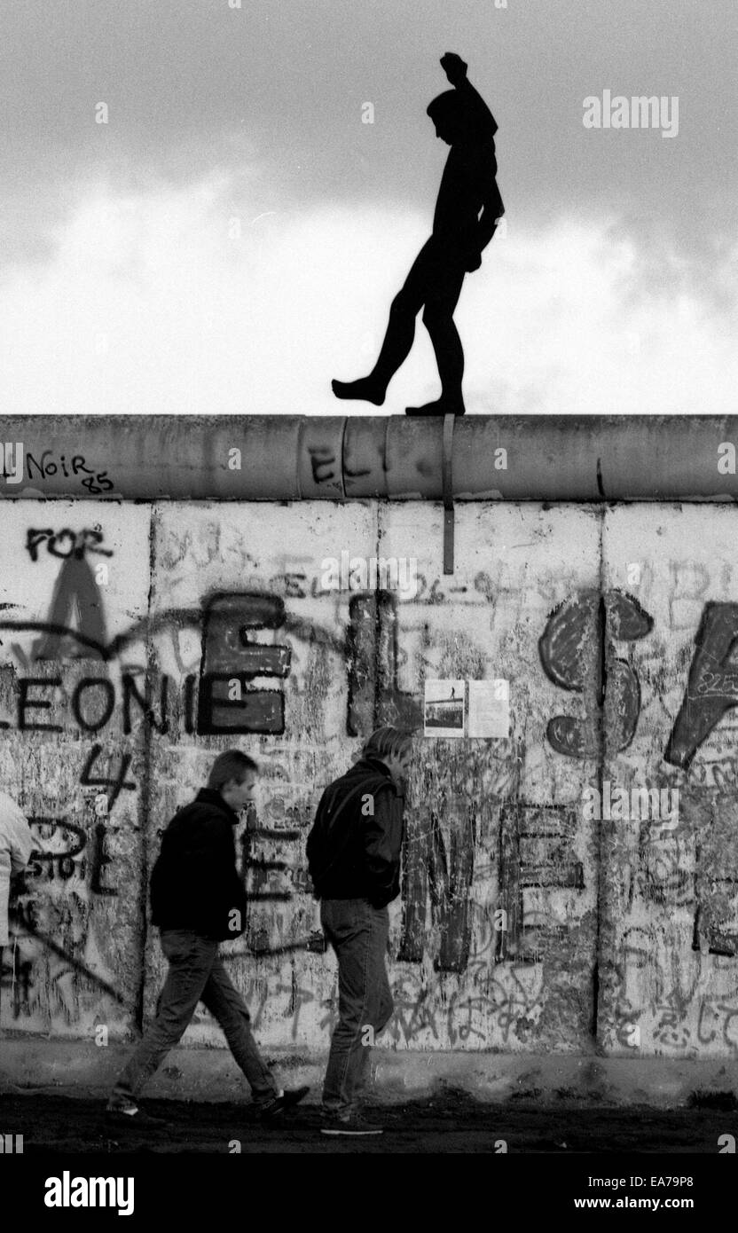 Domenica 9 luglio 2014 segna il venticinquesimo anniversario della caduta del muro di Berlino in Germania riunificata che la Germania occidentale e orientale. Nella foto: Novembre 9, 1989 - Berlino, Germania - due uomini a piedi sotto una silhouette di un uomo che cammina sulla sommità del muro di Berlino. © Scott A. Miller/ZUMAPRESS.com/Alamy Live News Foto Stock