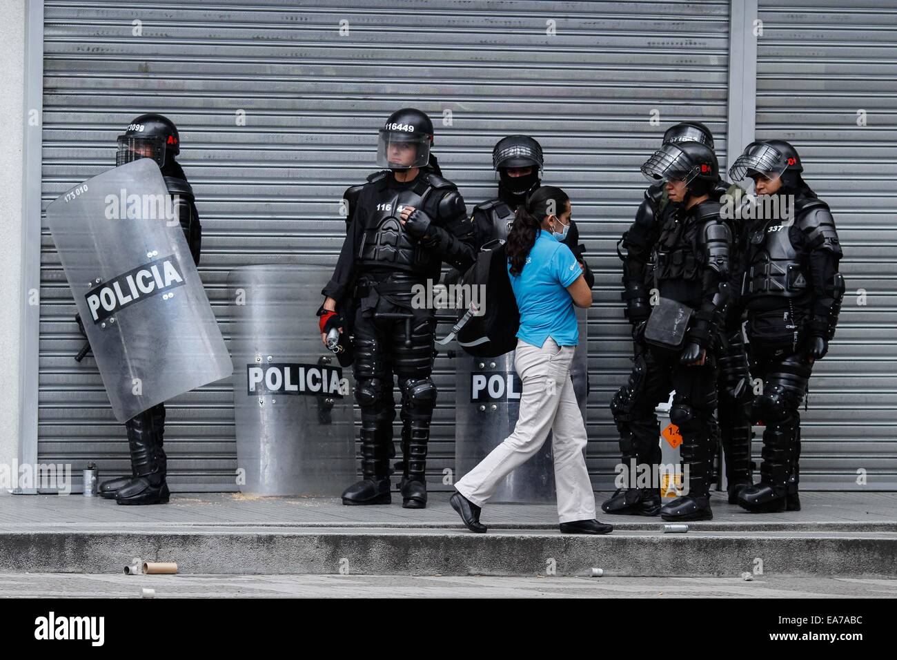 Bogotà, Colombia. 7 Nov, 2014. Un residente passeggiate nella parte anteriore dei poliziotti durante i disordini in Università pedagogica di Bogotà, a Bogotà, capitale della Colombia, su nov. 7, 2014. Secondo la stampa locale, diverse persone con cappuccio rioted nell'Università pedagogica di Bogotà, che ha portato a cinque feriti, tra loro due poliziotti con ustioni, due studenti e una guardia di sicurezza dell'università. © Jhon Paz/Xinhua/Alamy Live News Foto Stock