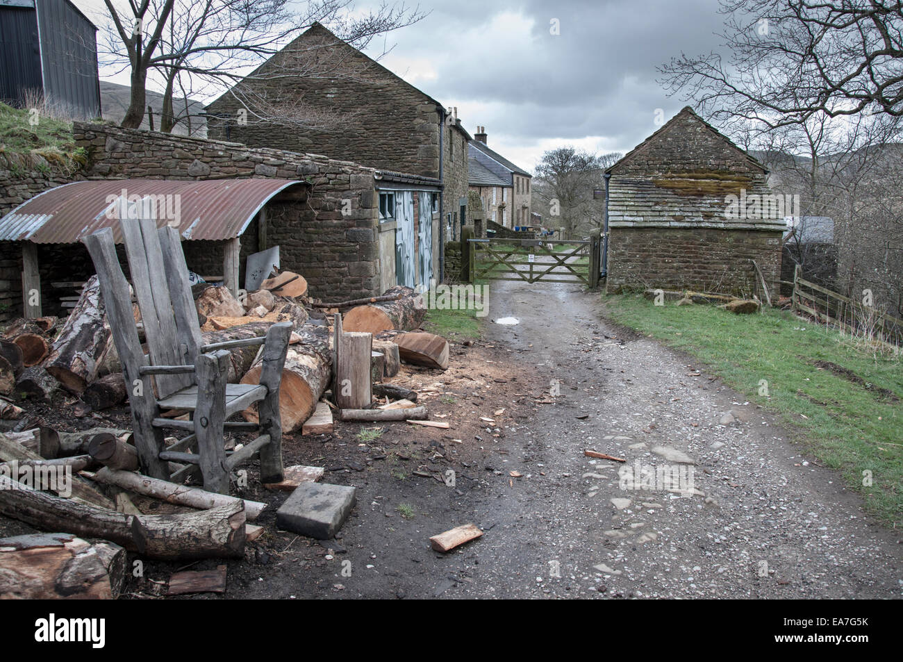 Rustico sedia in legno al di fuori degli edifici agricoli vicino a Edale nel Peak District. Pila di registro sul lato del percorso. Foto Stock