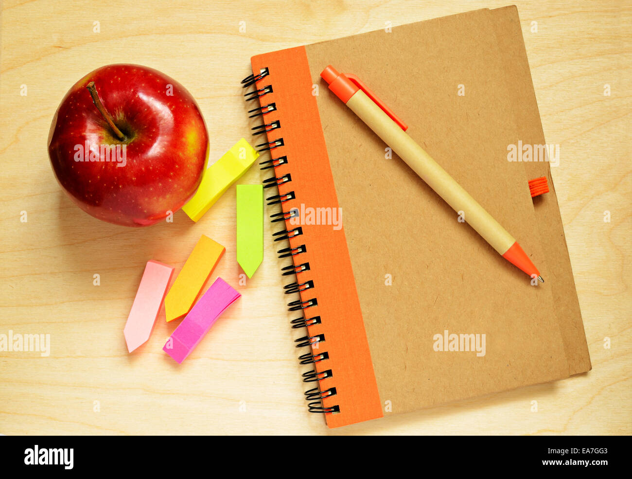 Notebook, penna, adesivi e apple sulla scrivania in legno Foto Stock