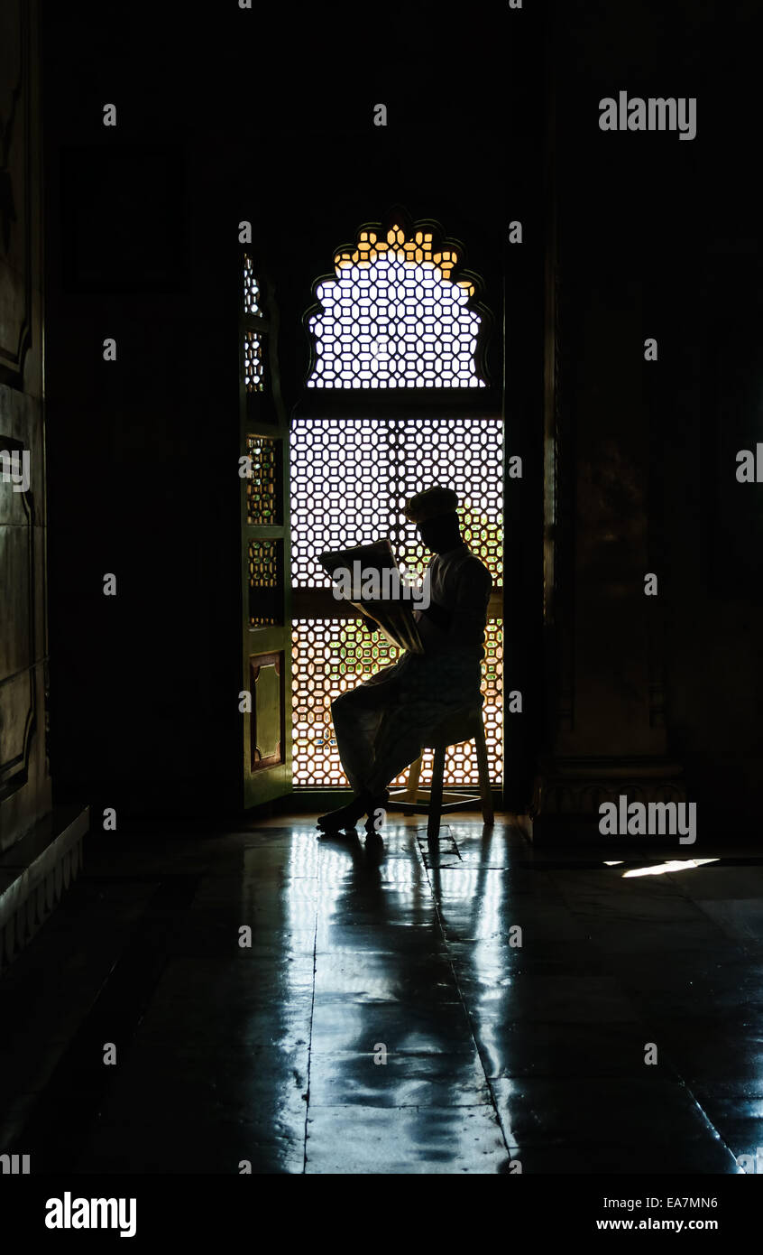 Uomo che legge il giornale in parte anteriore del vetro in silhouette, Jaswant Thada, Jodhpur, Rajasthan, India Foto Stock