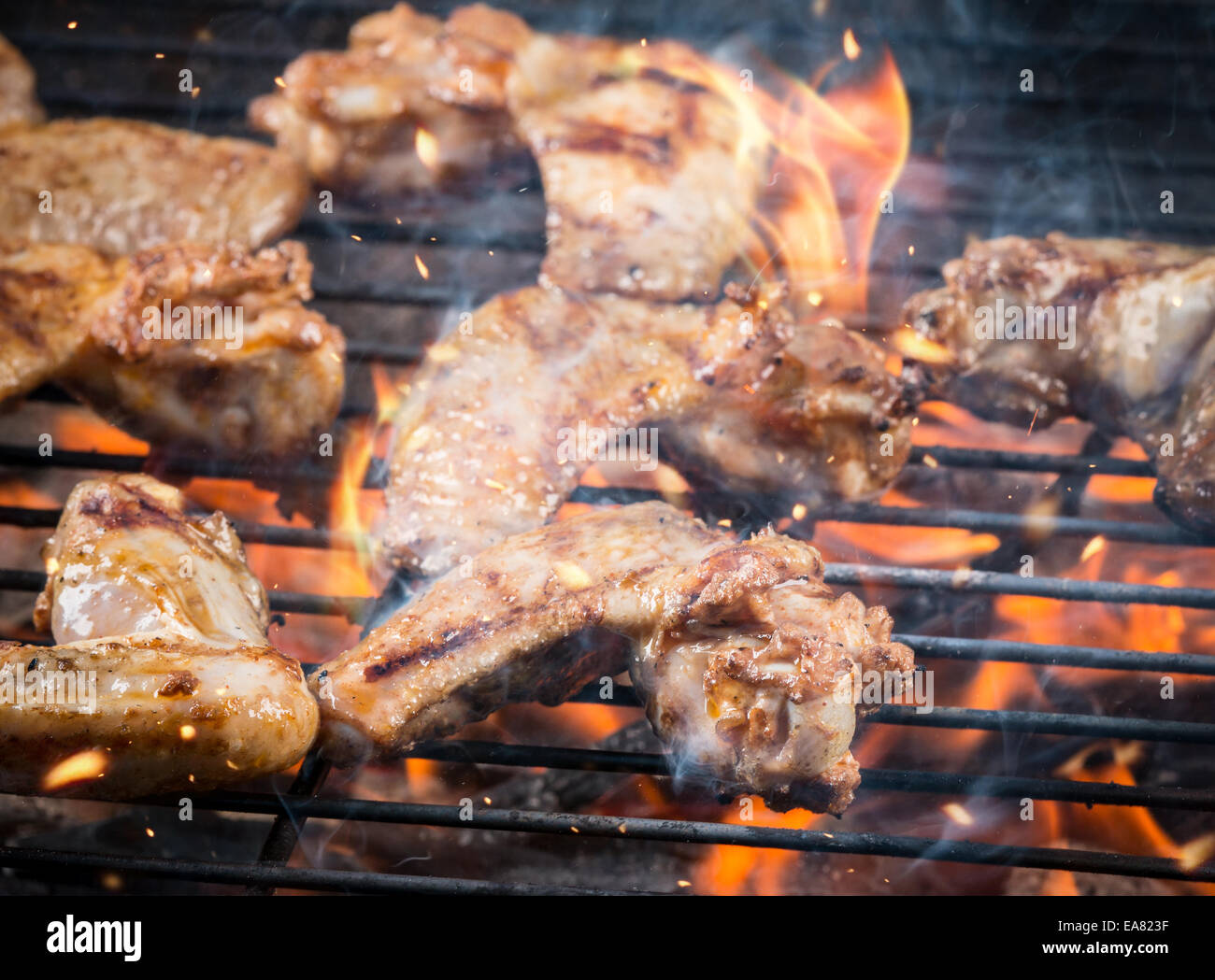 Ali di pollo su barbecue grill con il fuoco Foto Stock