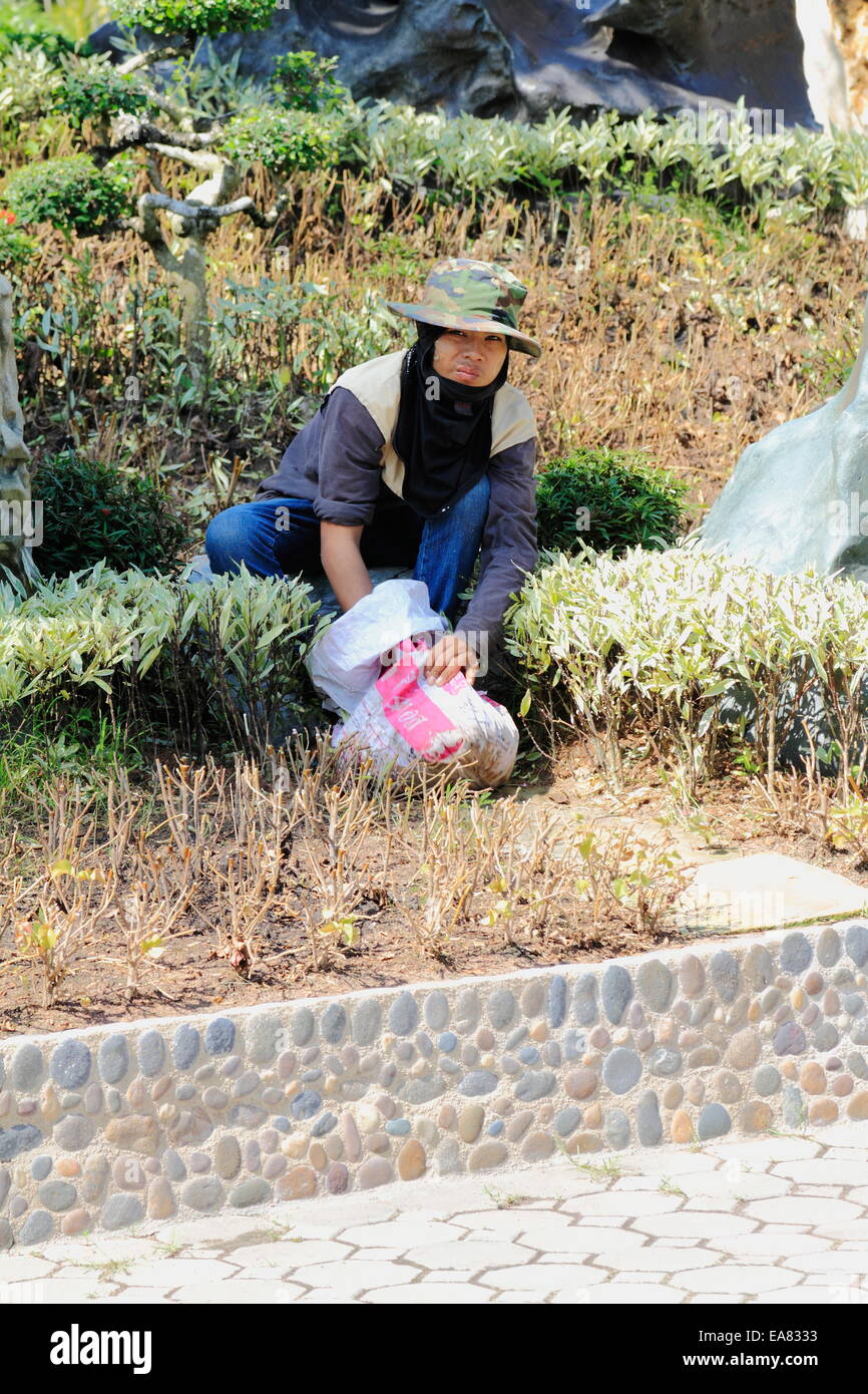 Una donna tailandese lavoratore è al lavoro sul terreno si inginocchiano Parco di Million Years Stone & Pattaya Crocodile Farm, Pattaya, Thailandia. Foto Stock