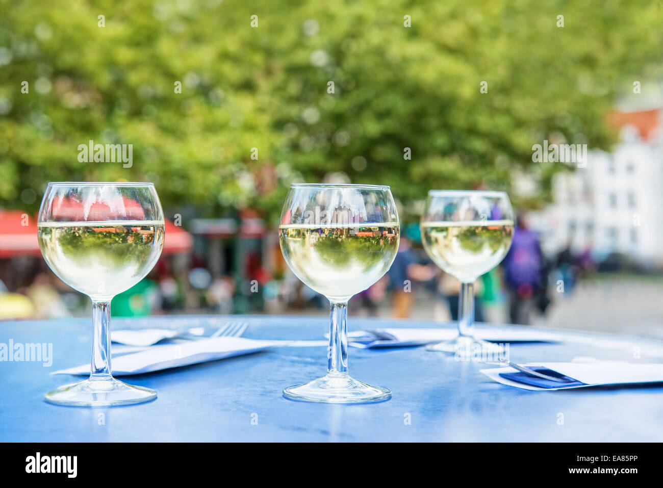 Tre Bicchieri di vino bianco e sagome di persone in parc Foto Stock