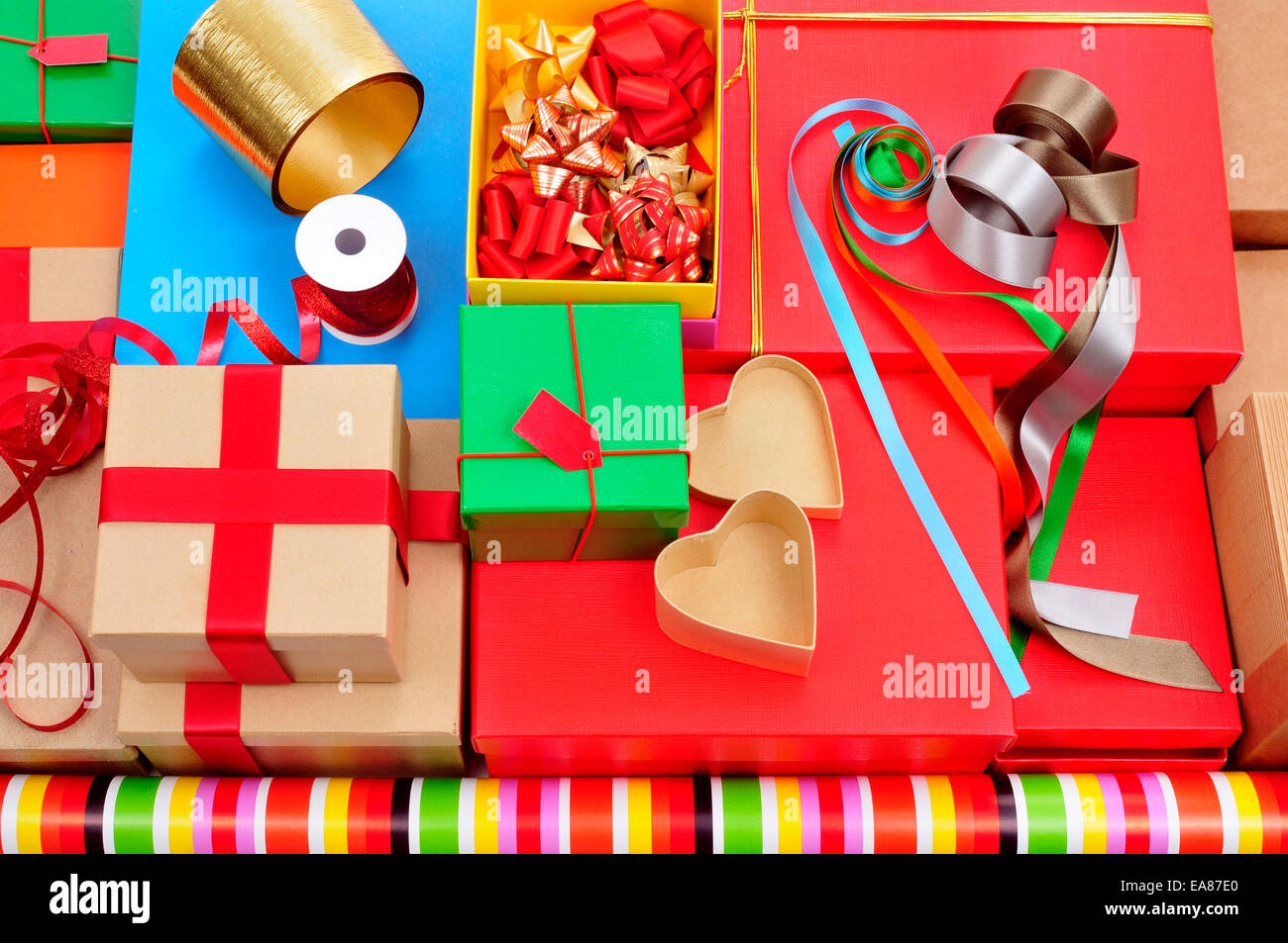 Una pila di scatole diverse, la carta di avvolgimento, nastro e archetti in nastro di diversi colori per preparare dei regali Foto Stock