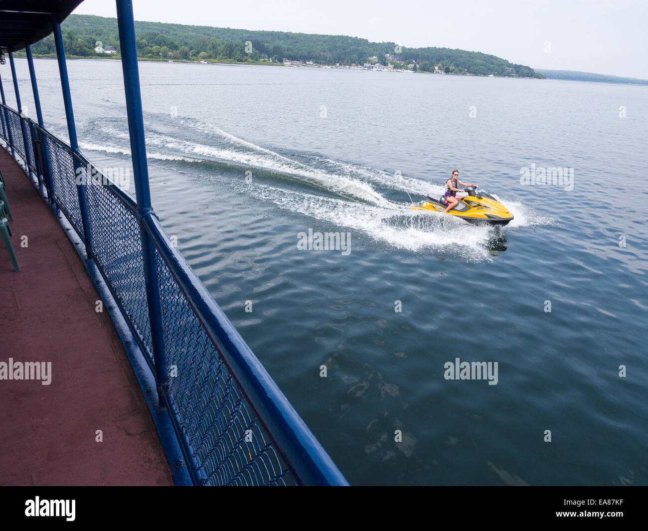 Accelerando da. Un jet ski barca con una donna alla velocità di guida passato un vecchio inizio xx secolo barca. Foto Stock