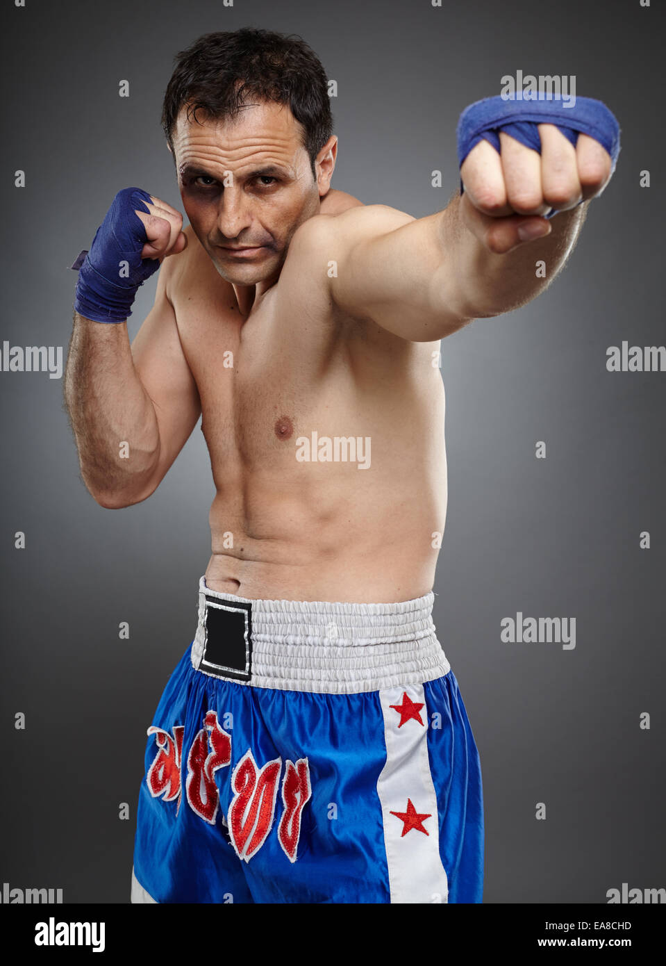 Muay Thai o kickbox fighter con i lividi e il sangue sul suo volto, gettando un punzone diretto Foto Stock