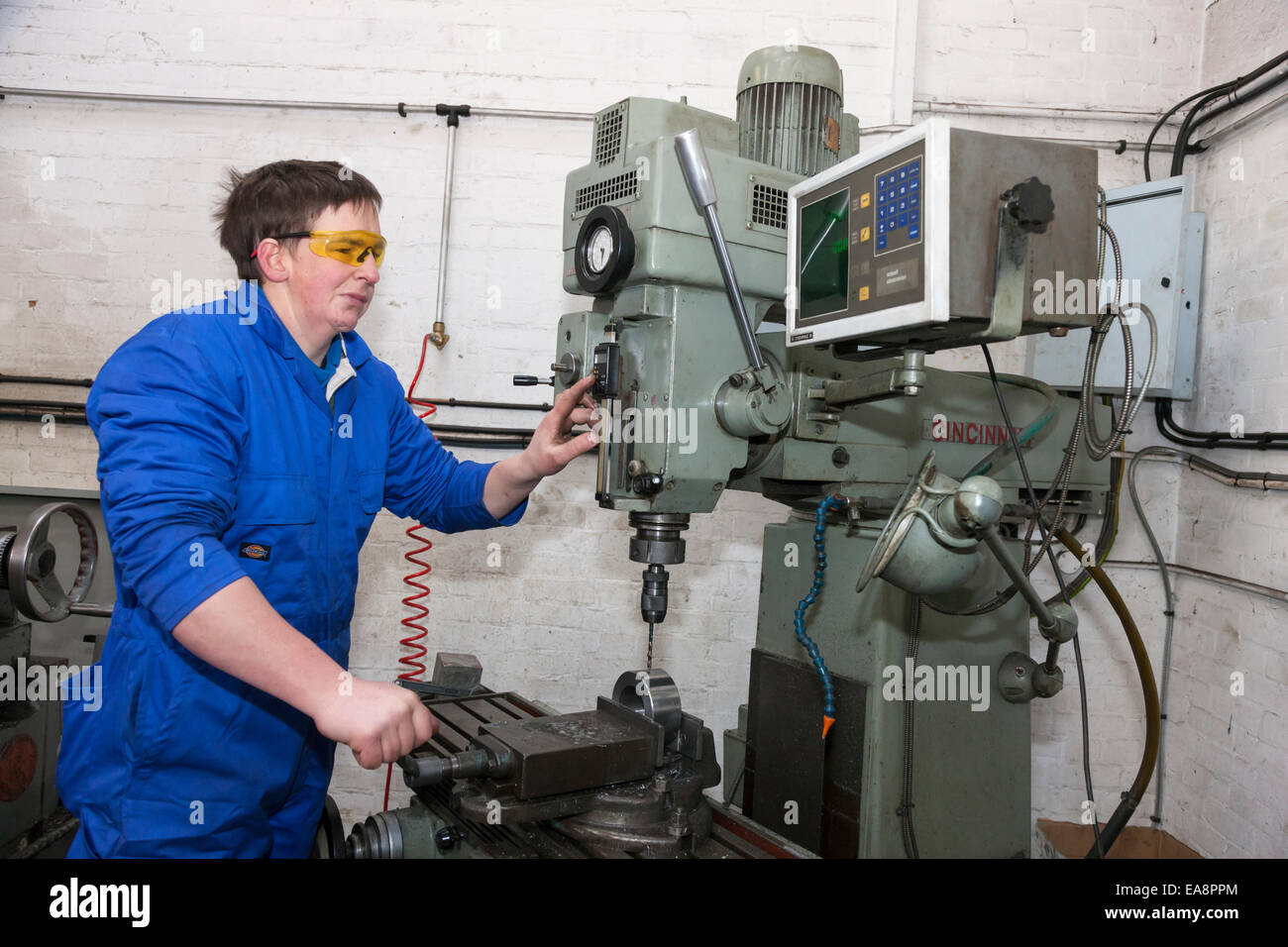 Tecnico su una macchina perforatrice strumento utilizzato nella fabbricazione di componenti idraulici Foto Stock