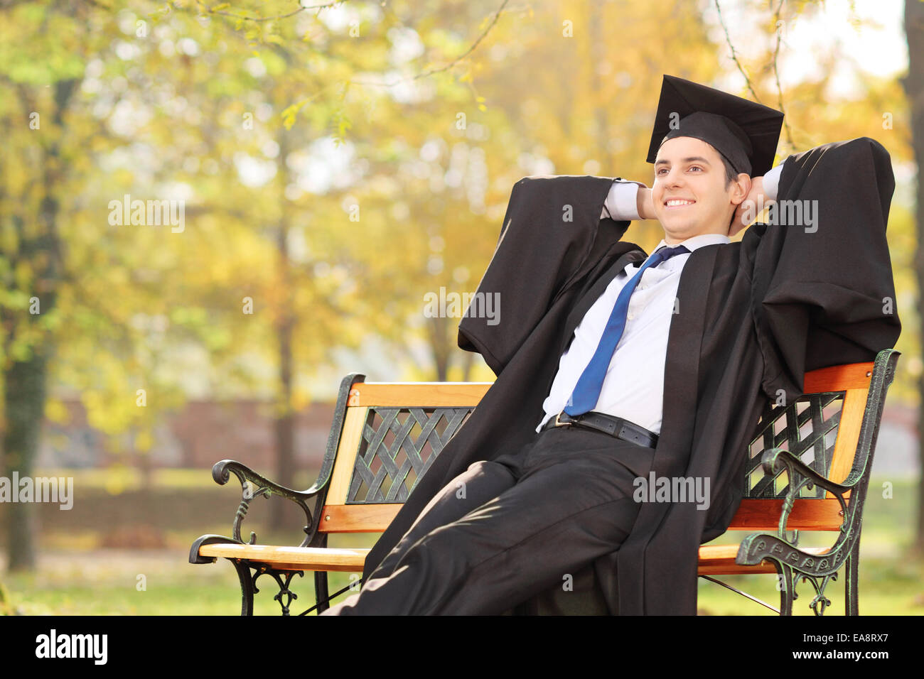 Rilassata studente laureato seduta su una panchina nel parco Foto Stock