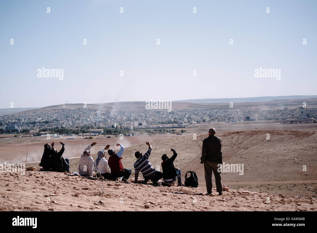 Profughi curdi guarda la allied aria investe in Kobani da una collina presso il bagno turco e la frontiera siriana, Turchia Foto Stock