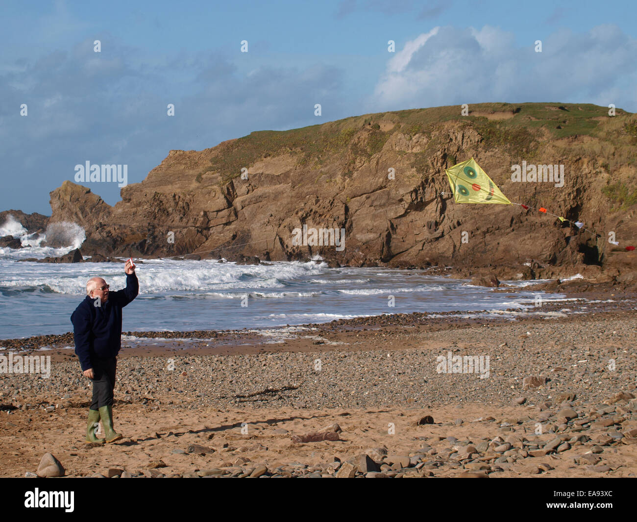 Titolare di pensione o di rendita giocando con un aquilone al mare, Bude, Cornwall, Regno Unito Foto Stock