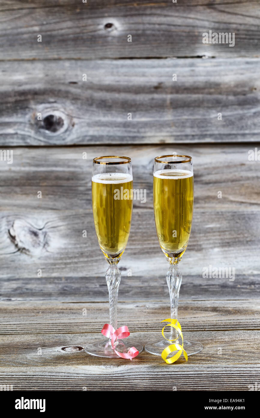 L'immagine verticale di Golden champagne in eleganti bicchieri in legno rustico con nastri Foto Stock