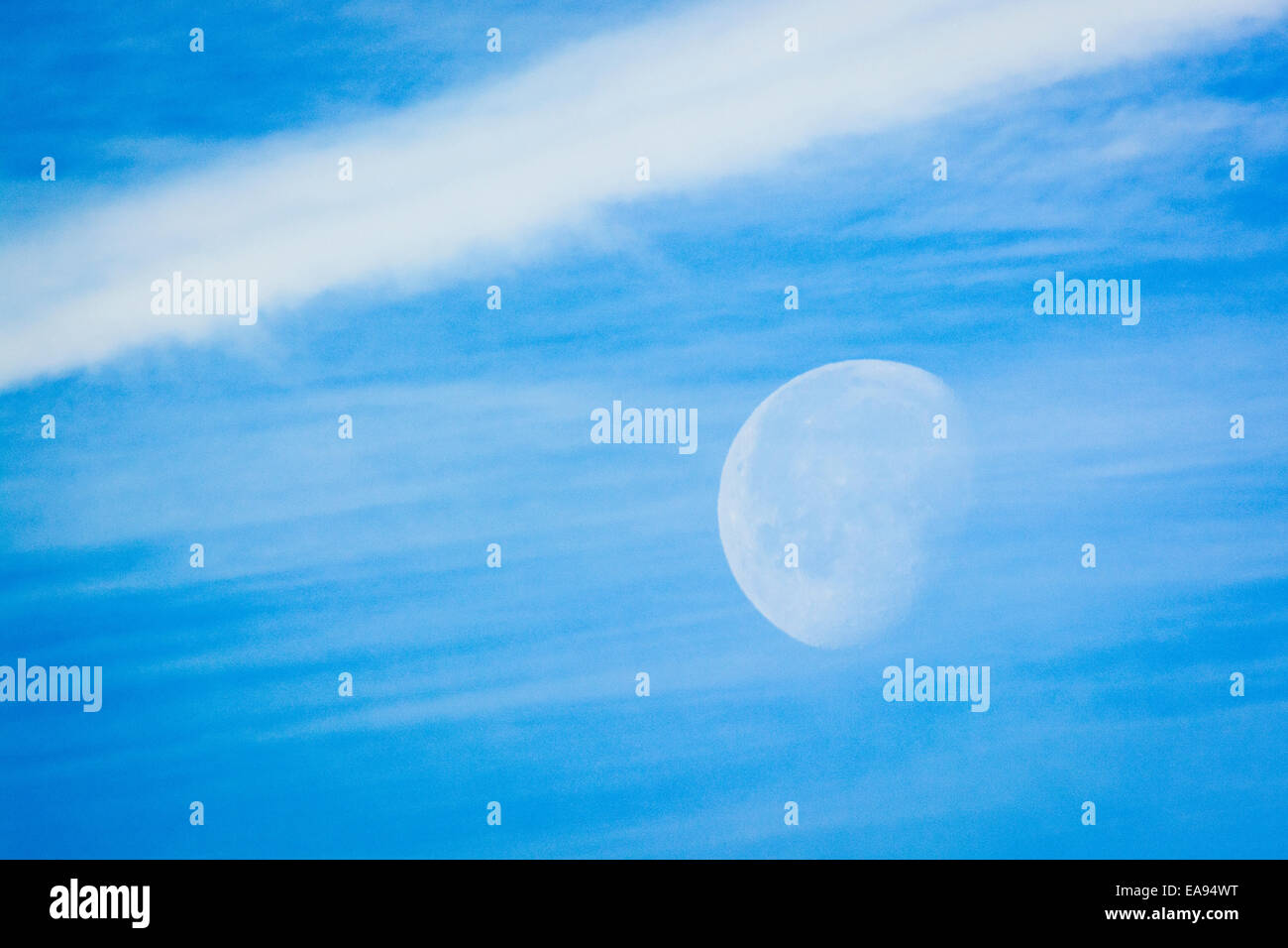 La luce diurna luna scena attraverso mattina vapore e contrails. Foto Stock