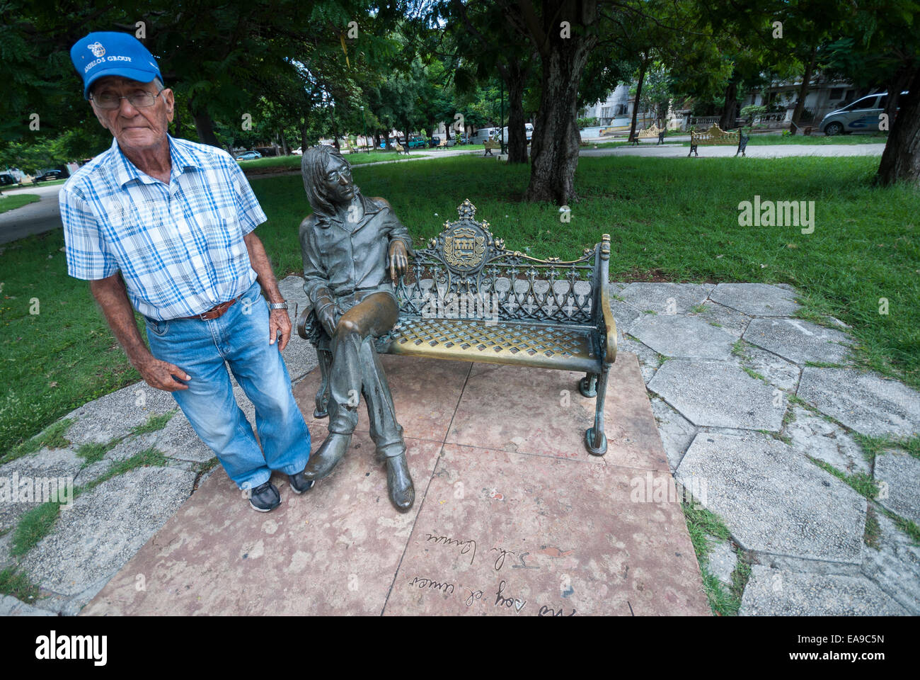 Una guardia di sicurezza che ha il compito di mettere gli occhiali di John Lennon scultura per i turisti al Parque John Lennon in Havana Cuba Foto Stock