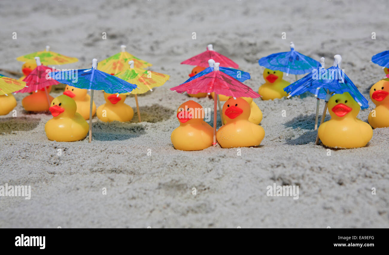 Le papere di gomma a rilassarci in spiaggia sotto gli ombrelloni. Foto Stock