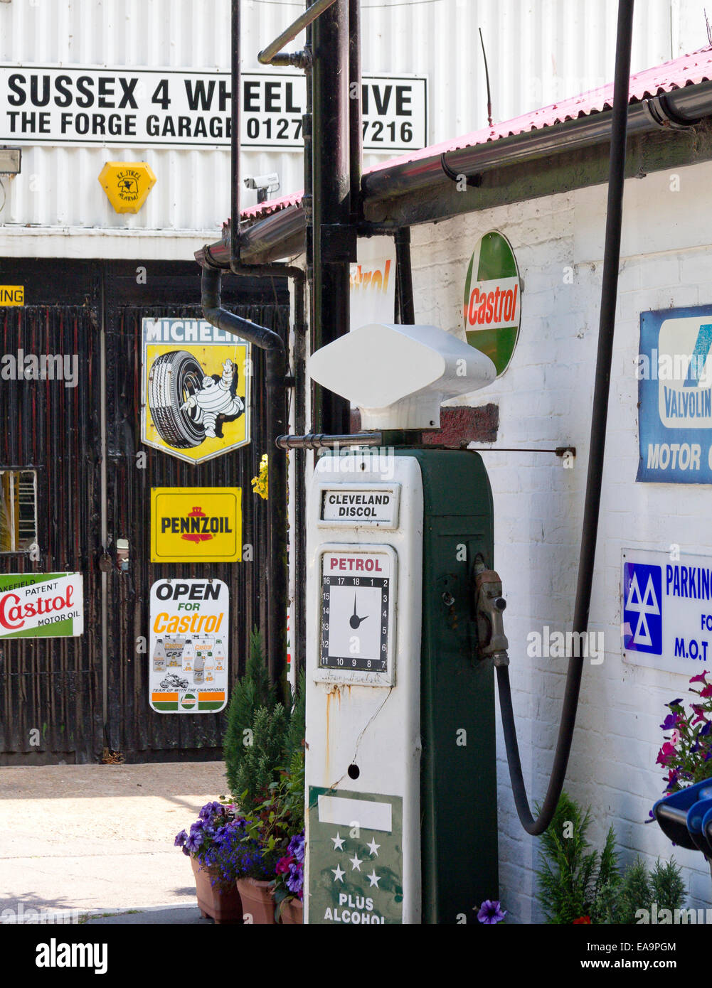 Un vintage pompa benzina in un garage a Sompting, West Sussex, Regno Unito con la vecchia pubblicità di marchi come la Michelin, Castrol e Val Foto Stock