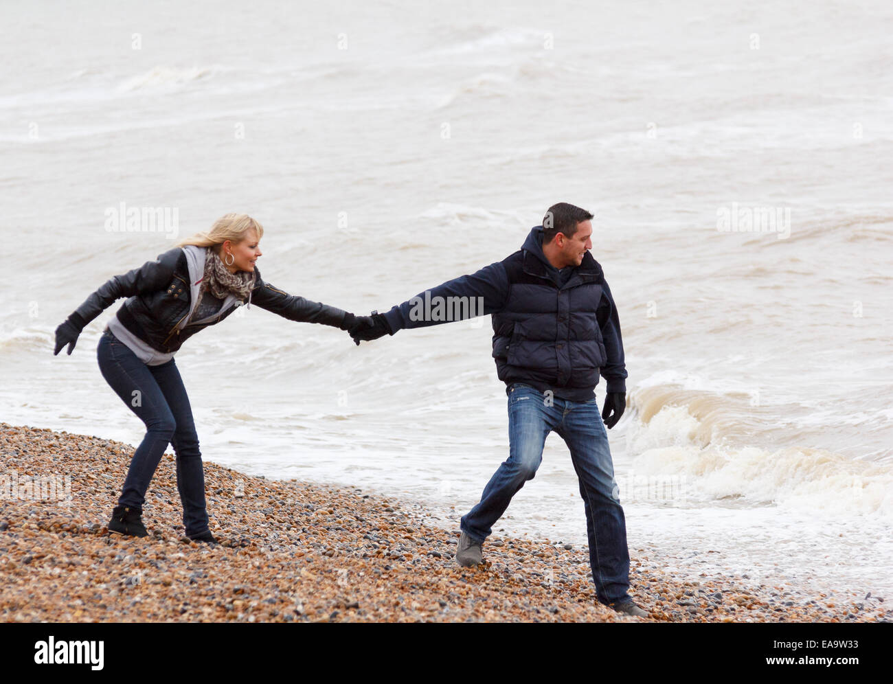Un giocoso giovane godendo una giornata nella località balneare inglese a Brighton in caldo abbigliamento invernale Foto Stock