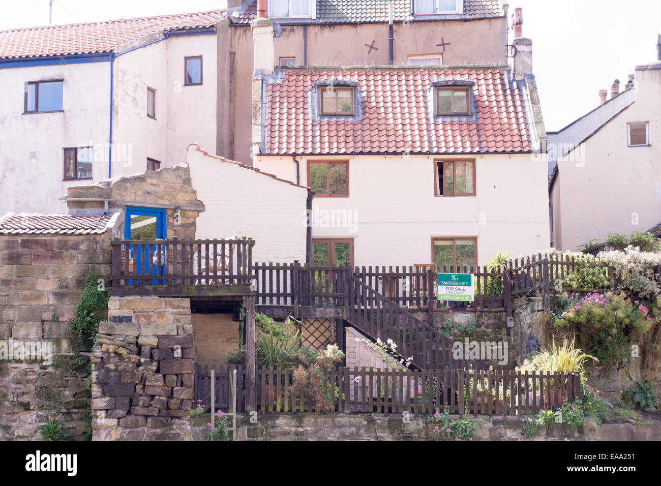North Yorkshire Coast, tradizionali case di villaggio con pareti in pietra, recinzioni in legno e giardini terrazzati in una giornata di sole in un ambiente costiero collinare Foto Stock