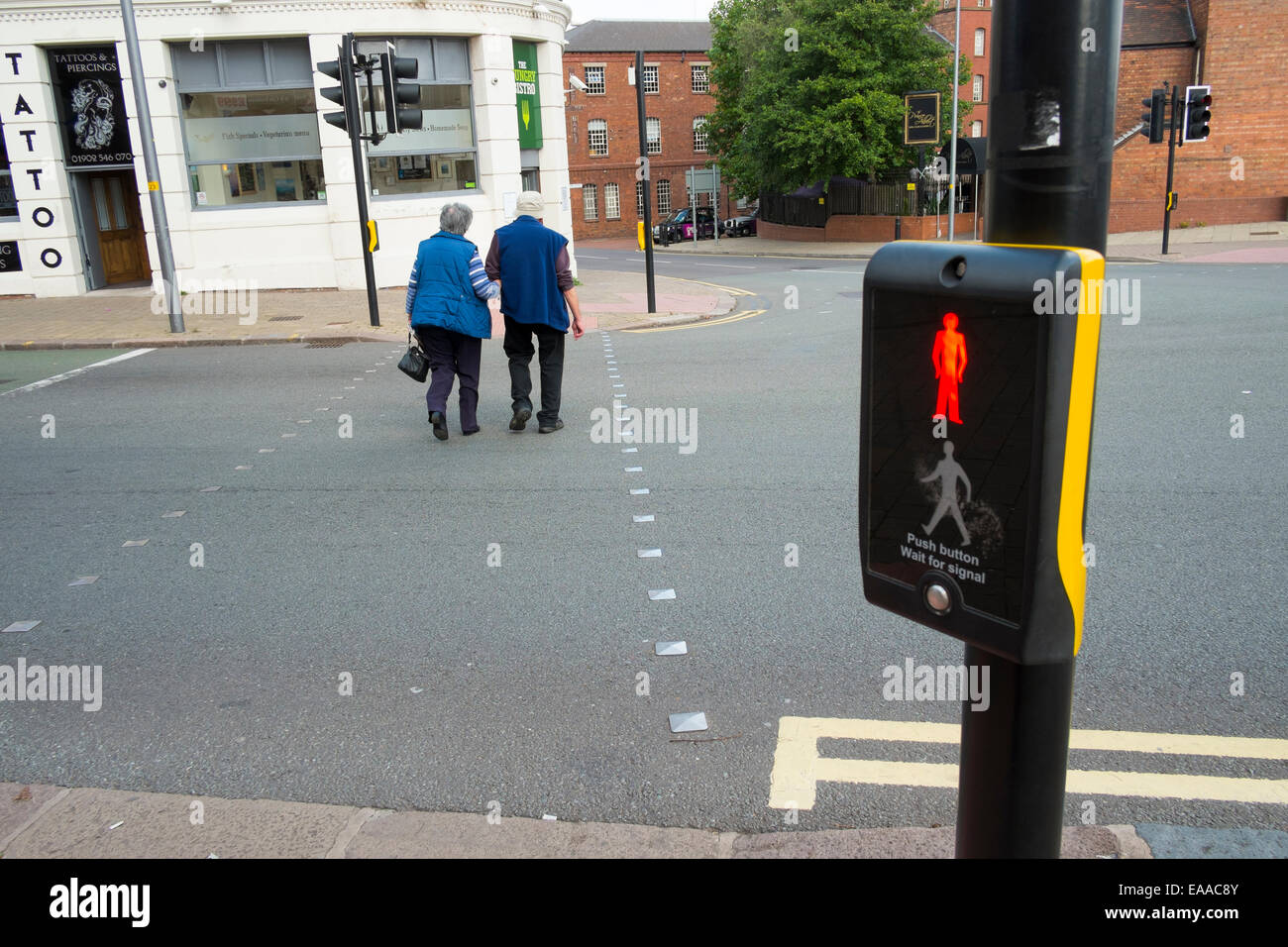 I cittadini anziani attraversare una strada a Wolverhampton usando un pellicano crossing, England, Regno Unito Foto Stock