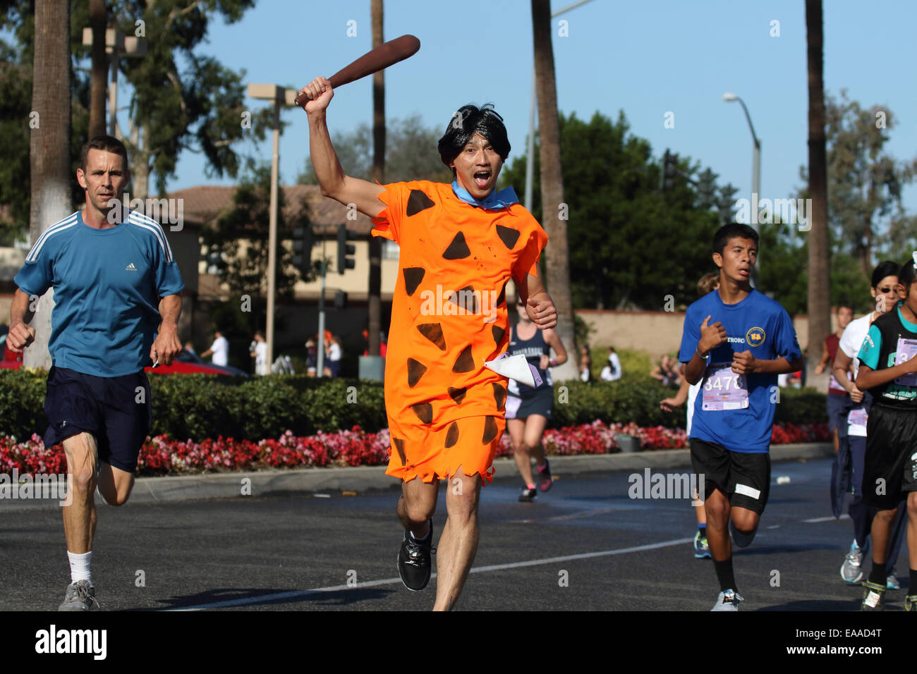 Runner vestito come Fred Flintstone dei compete in un 5k la gara su strada (Dino Dash) in Tustin California Foto Stock
