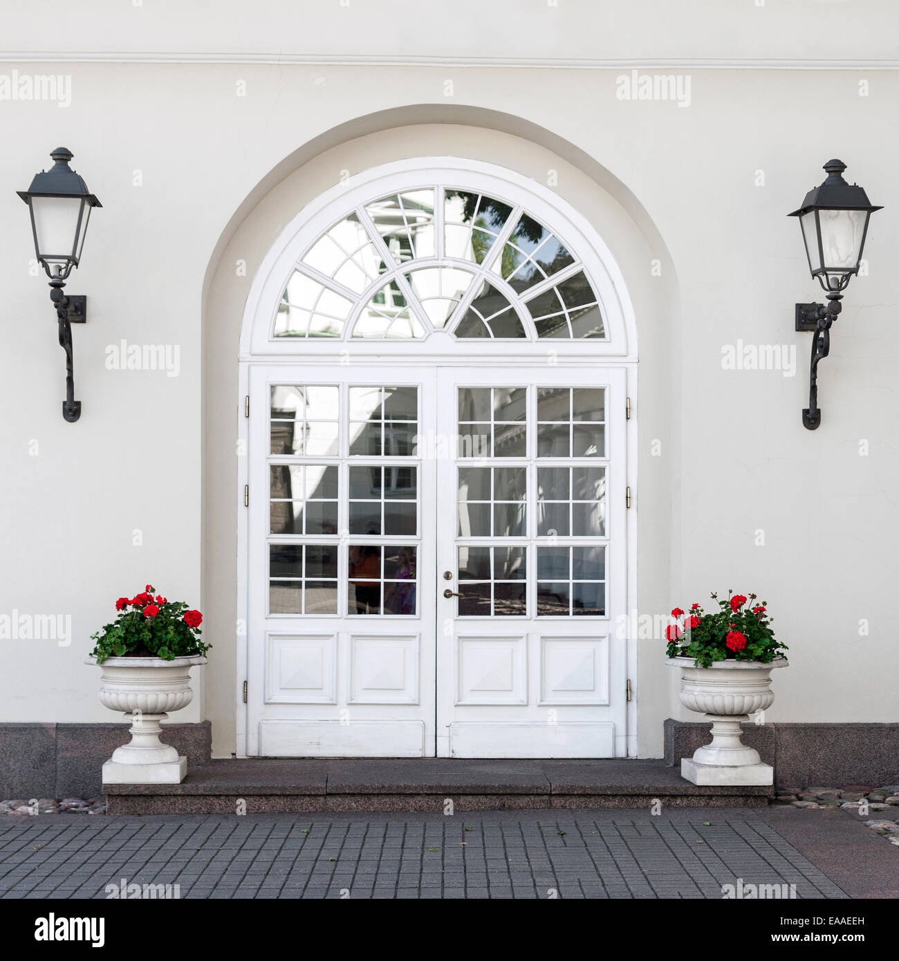 Un elegante stile classico doppia vetrata in vetro porta anteriore con lanterne anteriore e vasi di fiori Foto Stock