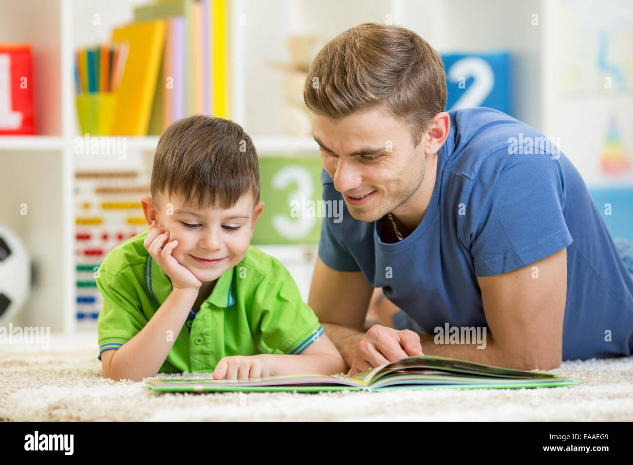 Kid boy e padre di leggere un libro sul pavimento per interni Foto Stock