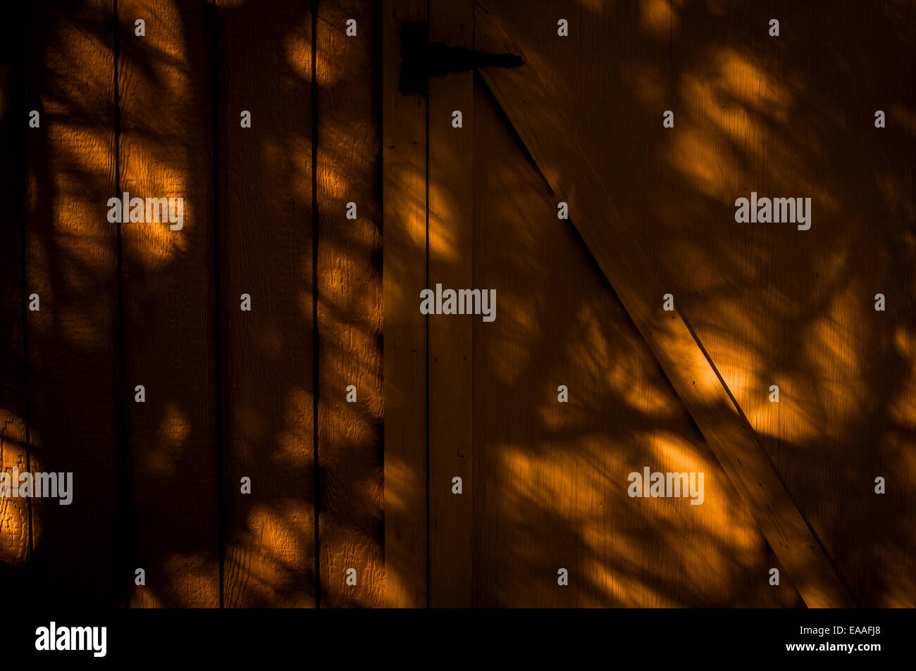 Vista del fienile porta nella parete in modelli di ombra e luce solare. Foto Stock