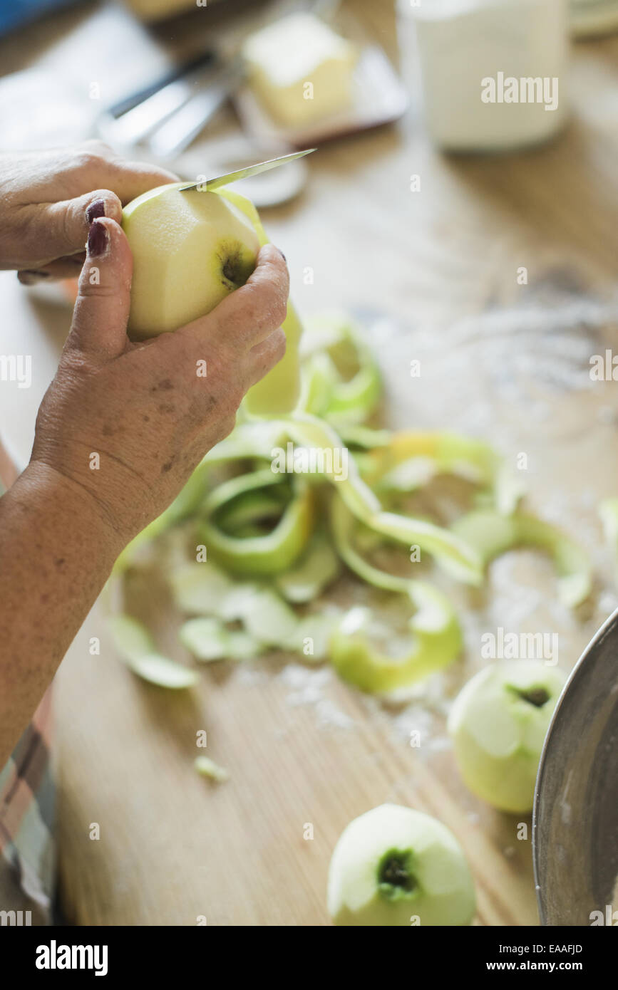 Una donna peeling un verde pelle apple. Foto Stock