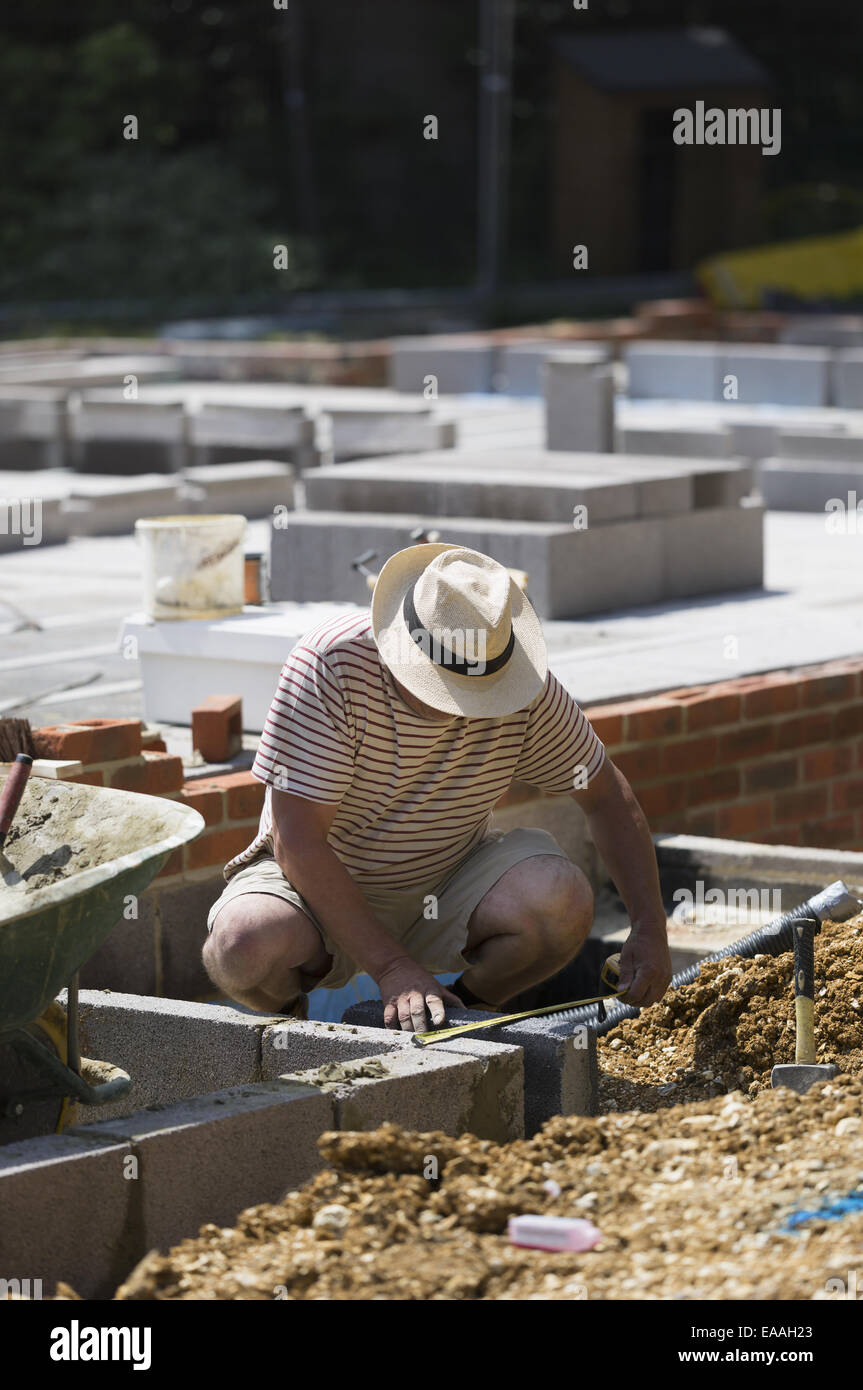 Uomo al lavoro su un cantiere, di porre le basi di un edificio. Foto Stock