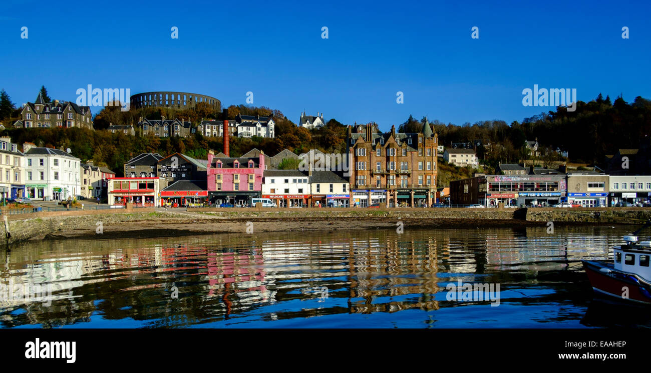 Di fronte al mare a Oban in Scozia con il rovinato McCaig's Tower sulla collina sopra Foto Stock