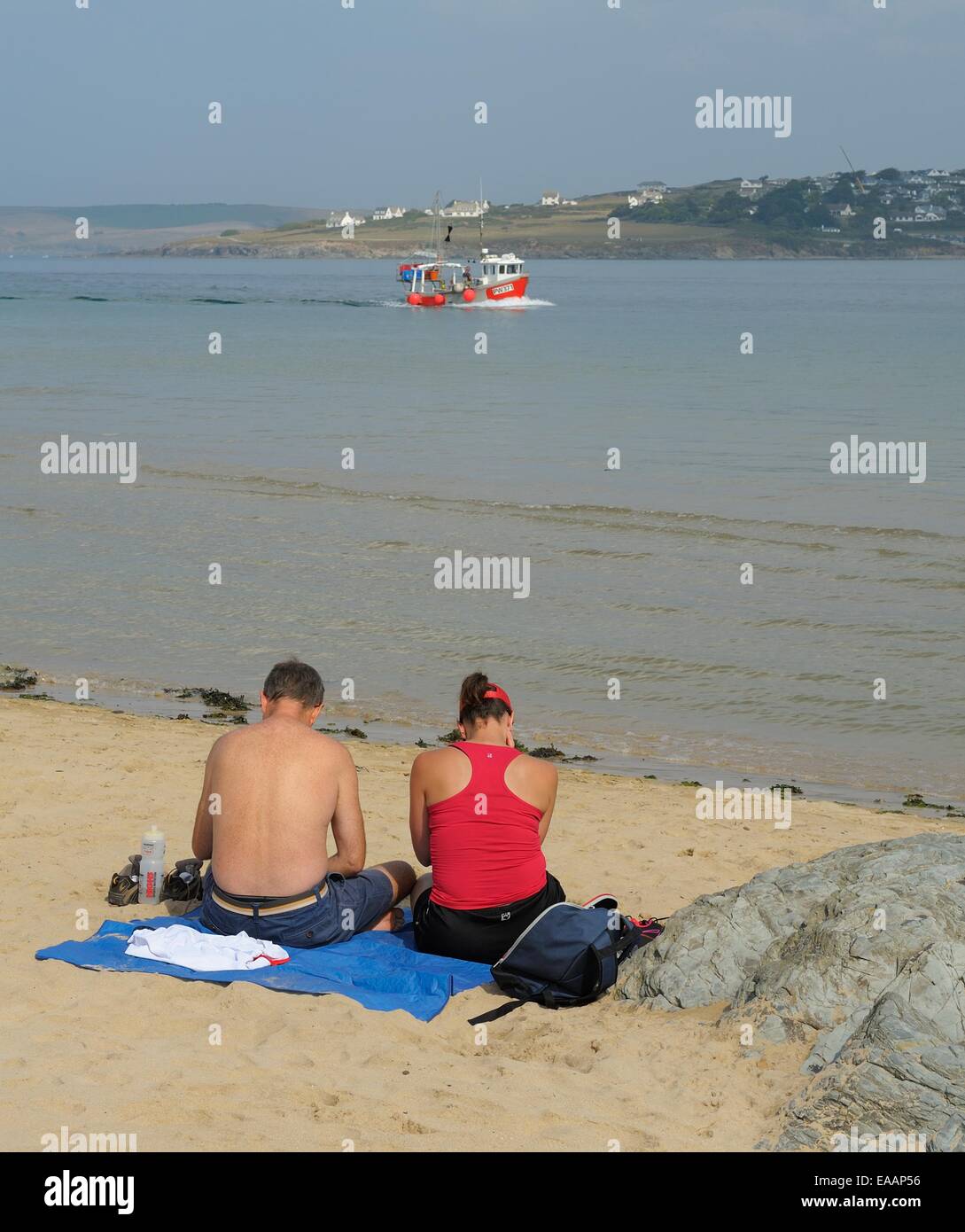 Un uomo e una donna seduta sulla spiaggia nella Camel Estuary,Padstow,Cornwall,Inghilterra Regno Unito Foto Stock