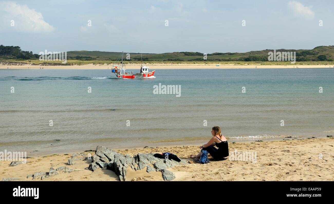 Una giovane donna seduta da sola sulla spiaggia nella Camel estuary,Padstow Cornwall Inghilterra Regno Unito Foto Stock