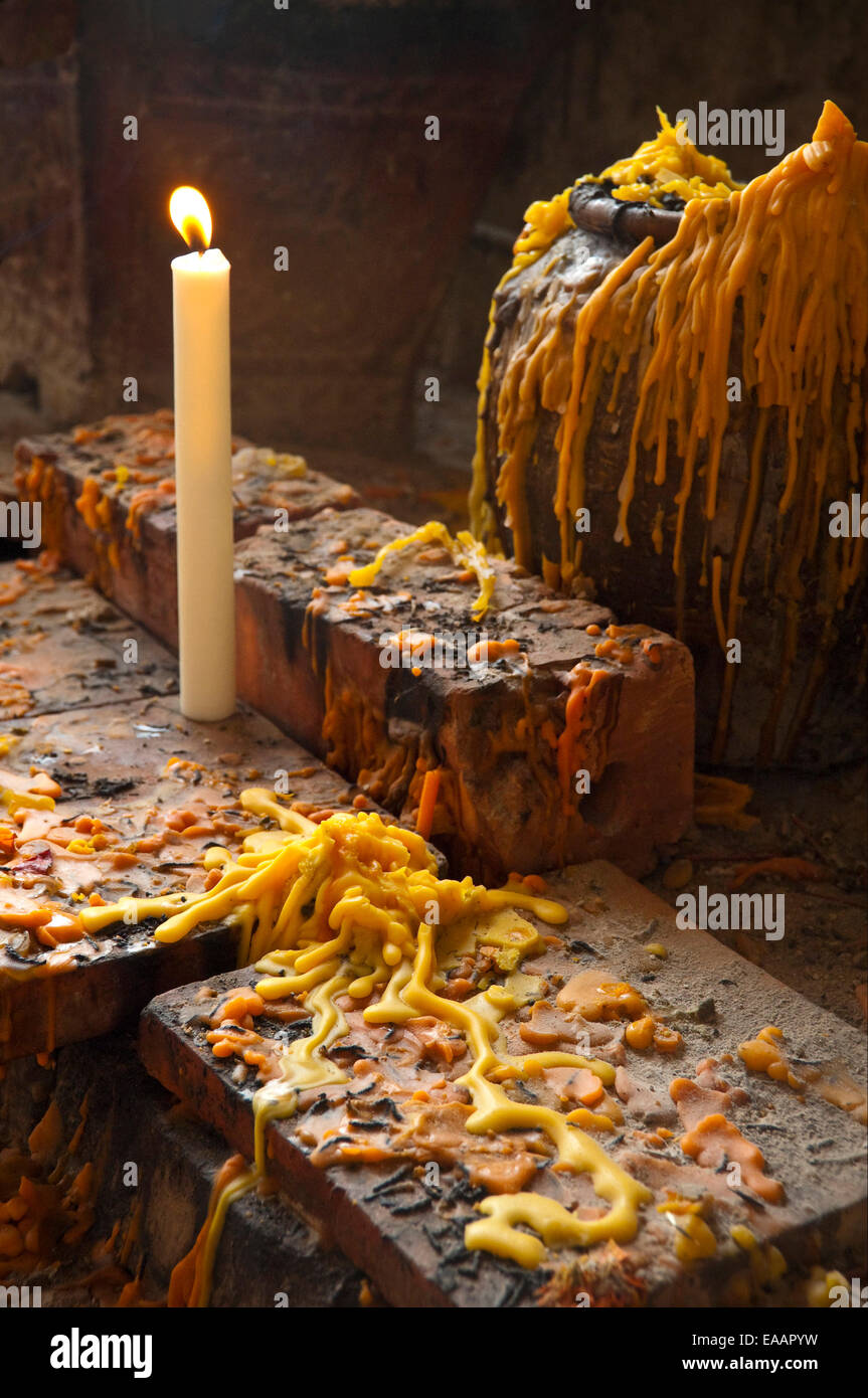 Verticale fino in prossimità di una illuminata candela votiva e strati di vecchia cera fusa in Pak Ou o Tam Ting grotte Foto Stock