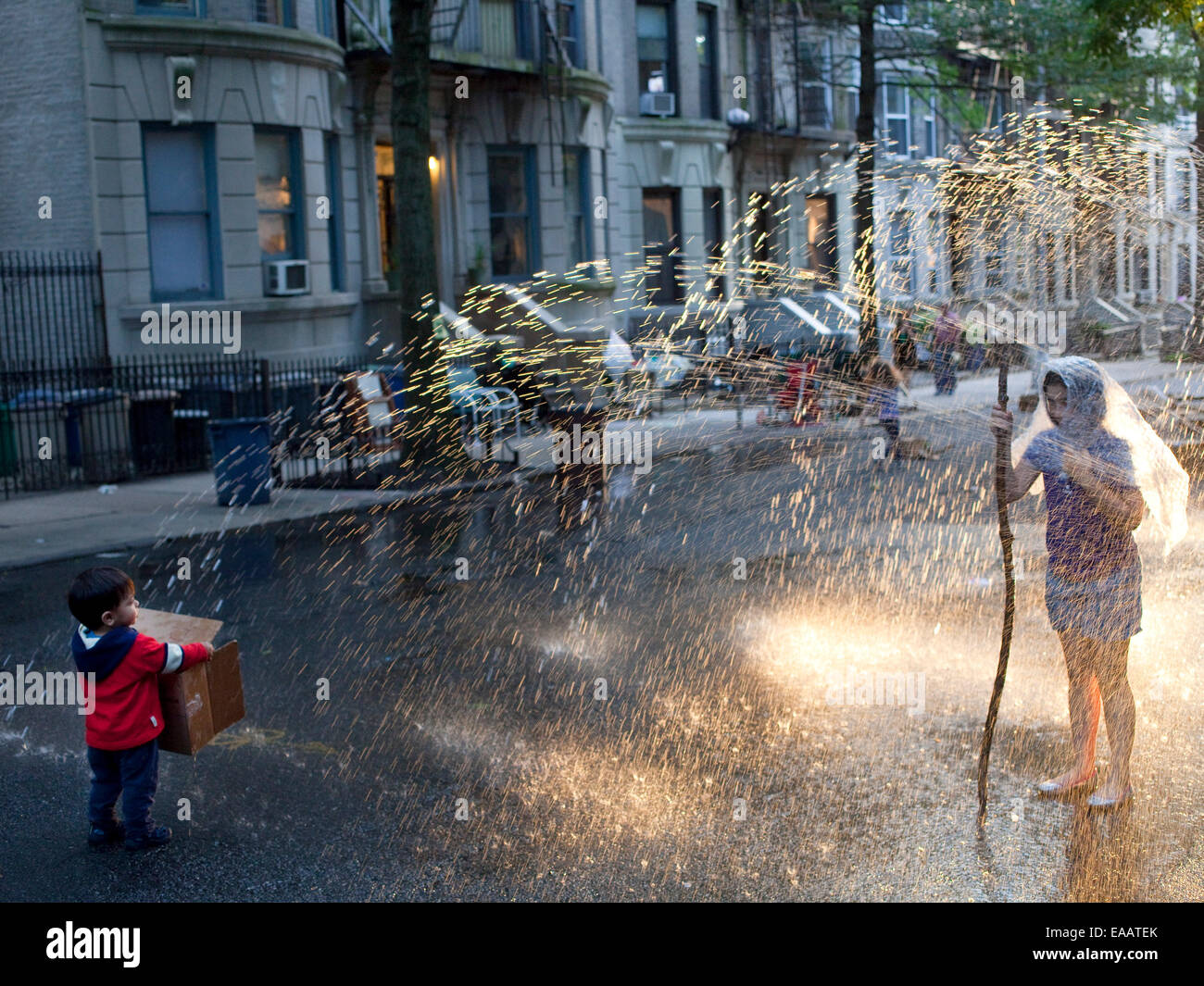 Bambini che giocano nella idrante antincendio sprinkler Brooklyn durante la festa dei blocchi. Foto Stock