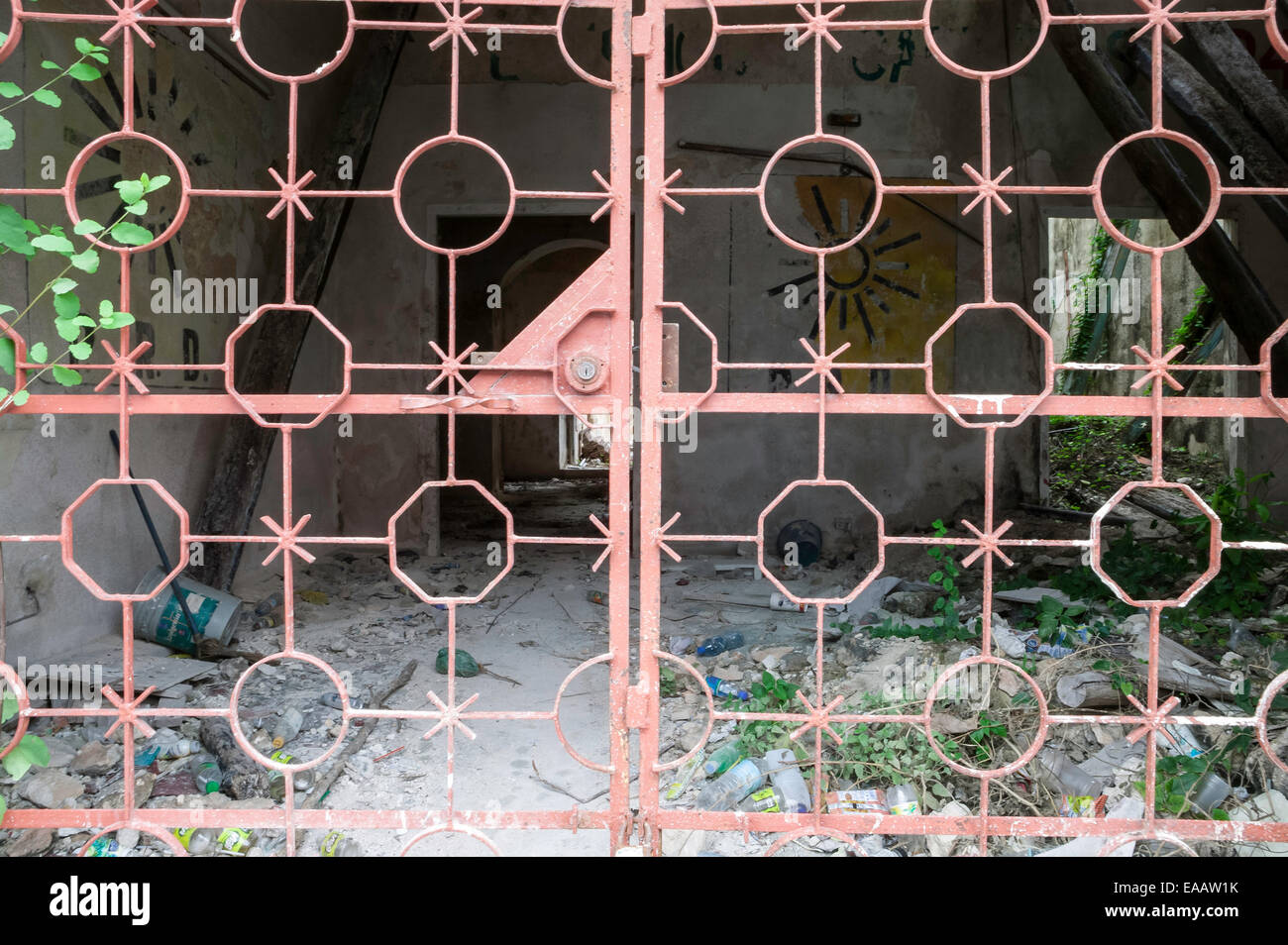 Vista degli interni spagnolo fatiscente casa coloniale attraverso un color salmone cancellata in ferro battuto, Campeche, Messico. Foto Stock
