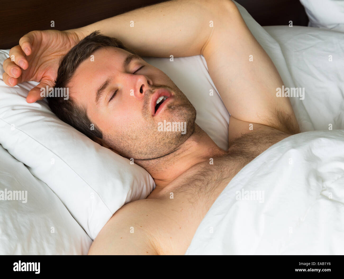 Un uomo dorme nel letto con il suo braccio Foto Stock