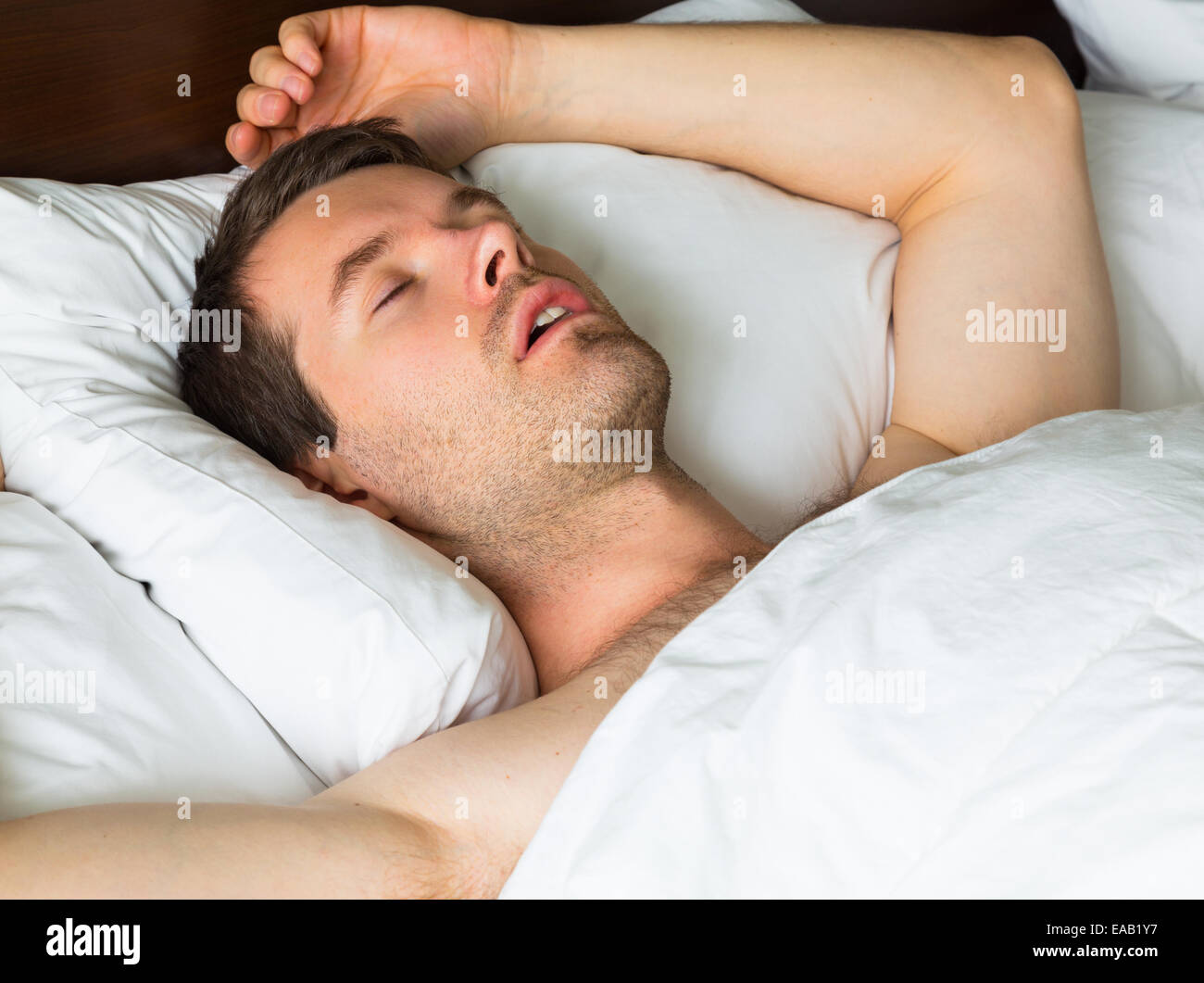 Un uomo dorme nel letto con il suo braccio Foto Stock