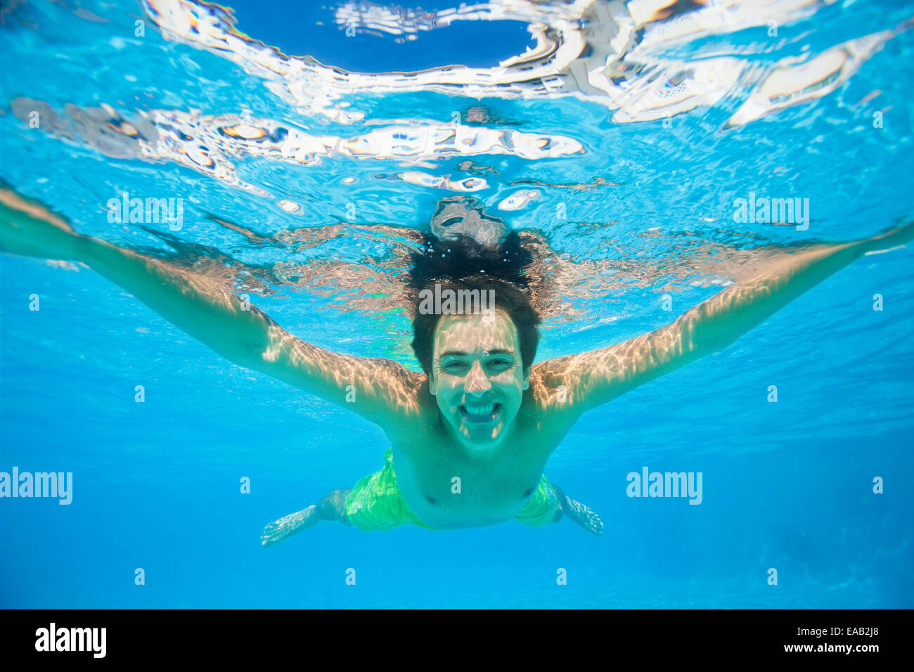 Uomo sorridente nuota sotto le acque cristalline Foto Stock