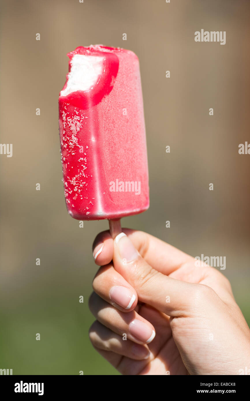 Ragazza mano azienda rosa morso gelati su stick Foto Stock