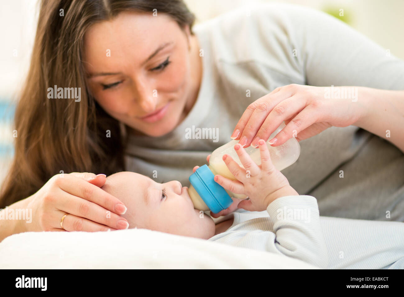 Madre a casa alimentazione bambino con una bottiglia di latte Foto Stock
