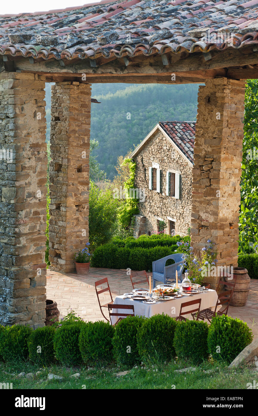 La tabella prevista per il pasto sul patio coperto di agriturismo nelle colline umbre Foto Stock