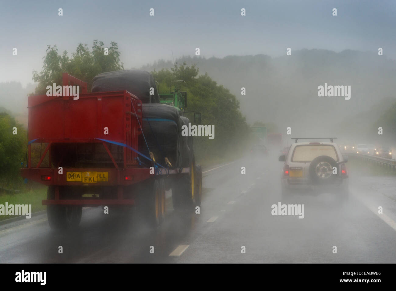 Il trattore con il rimorchio in autostrada in caso di pioggia Foto Stock