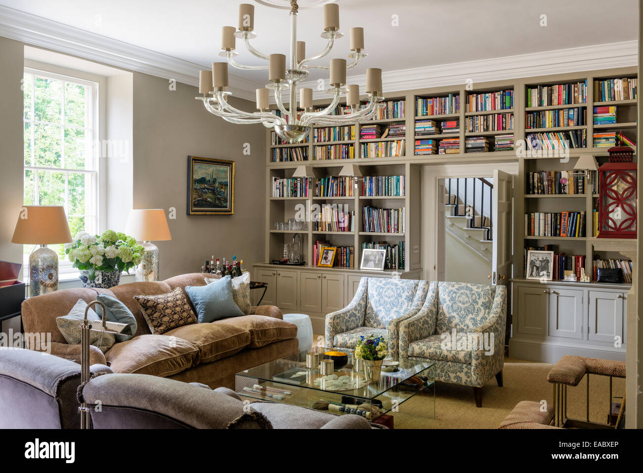 Lampadario in vetro di Murano e Kingscombe divani e sedie in salotto con incorporato di libro scaffali Foto Stock