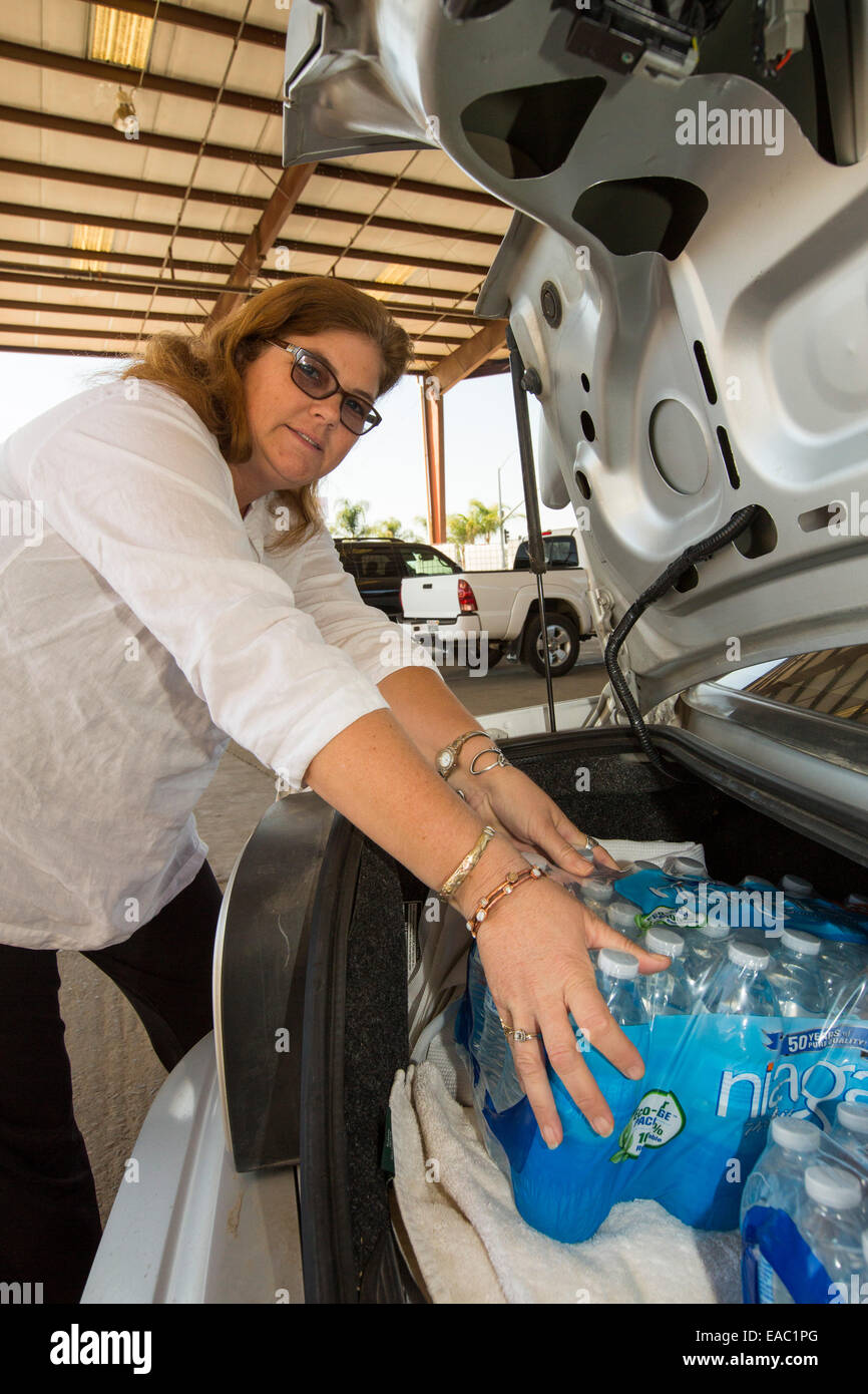 Una donna carica la sua automobile con acqua da un carità in Porterville la fornitura di acqua in bottiglia per case che non hanno avuto esecuzione w Foto Stock