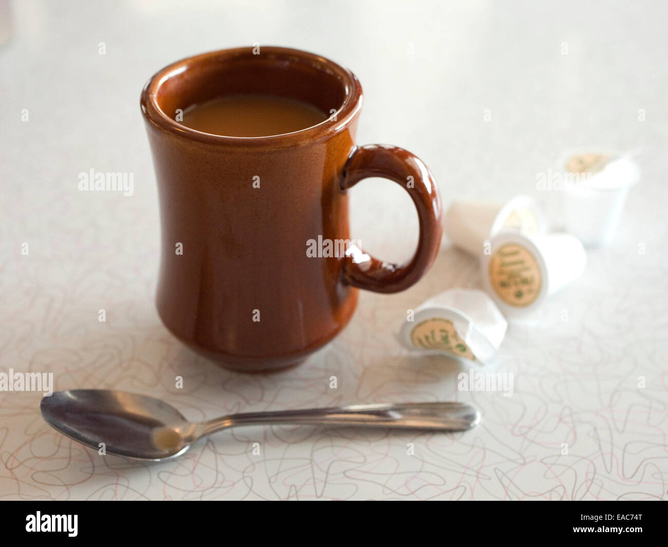 Una tazza di caffè e creamers di plastica in un diner Foto Stock