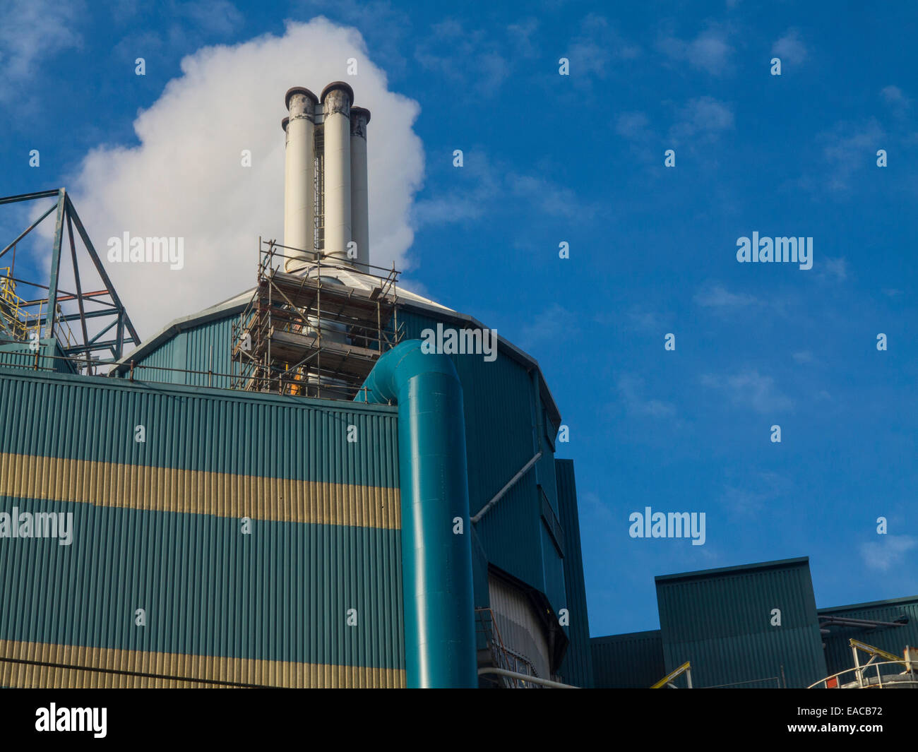 Una stazione di alimentazione emette vapore in una soleggiata cielo blu Foto Stock