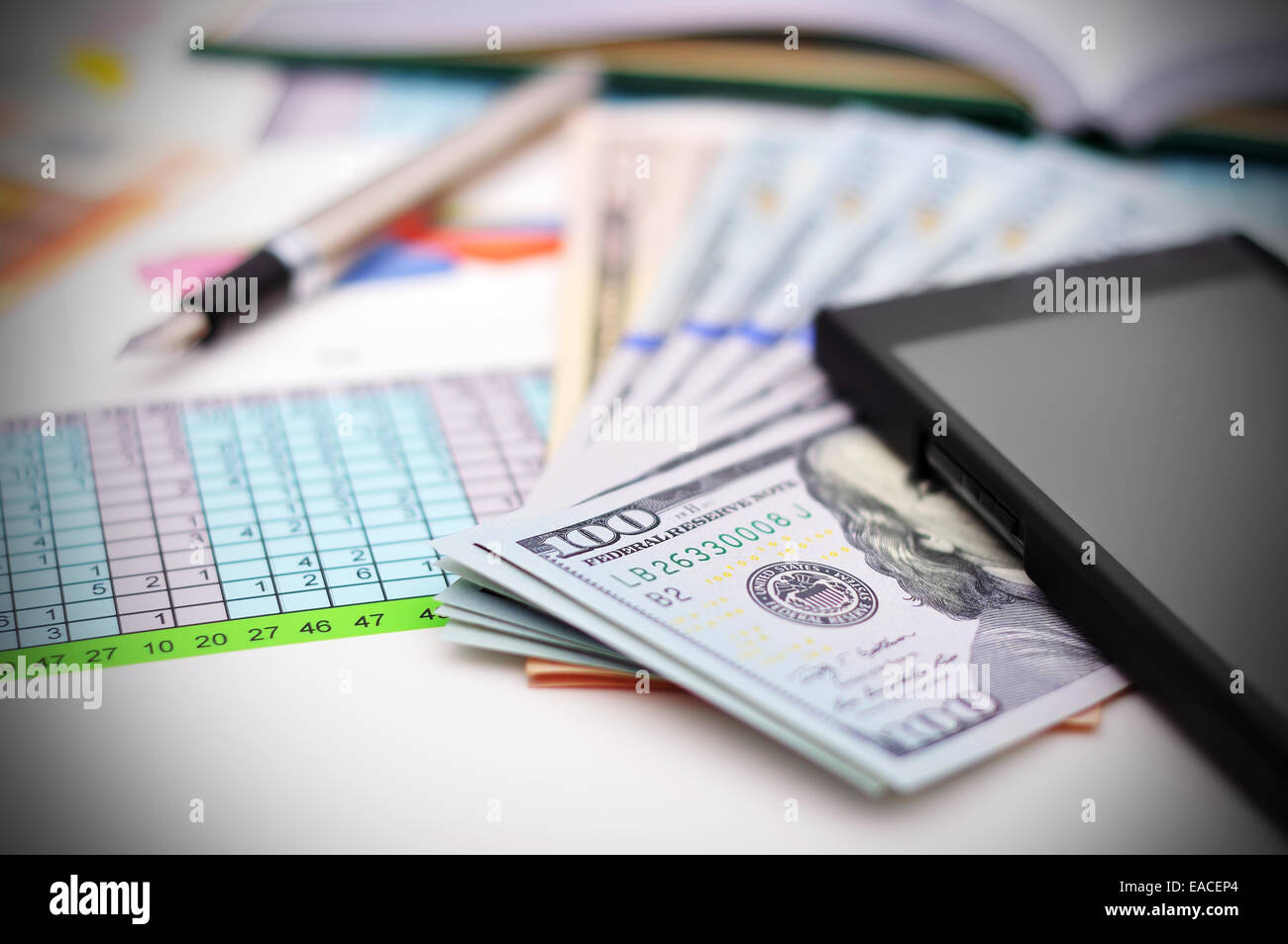 Relazione finanziaria sul tavolo con denaro, penna e telefono Foto Stock