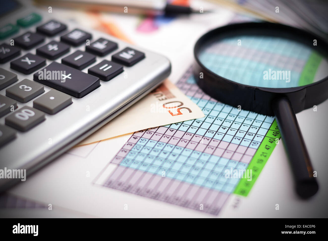 Tabella finanziaria con la calcolatrice e lente di ingrandimento Foto Stock
