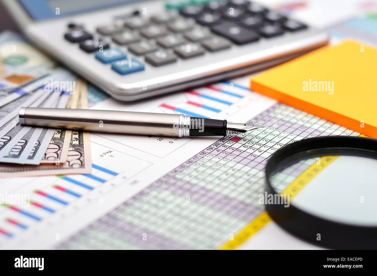 I grafici finanziari sulla tavola con il denaro, calcolatrice e penna Foto Stock